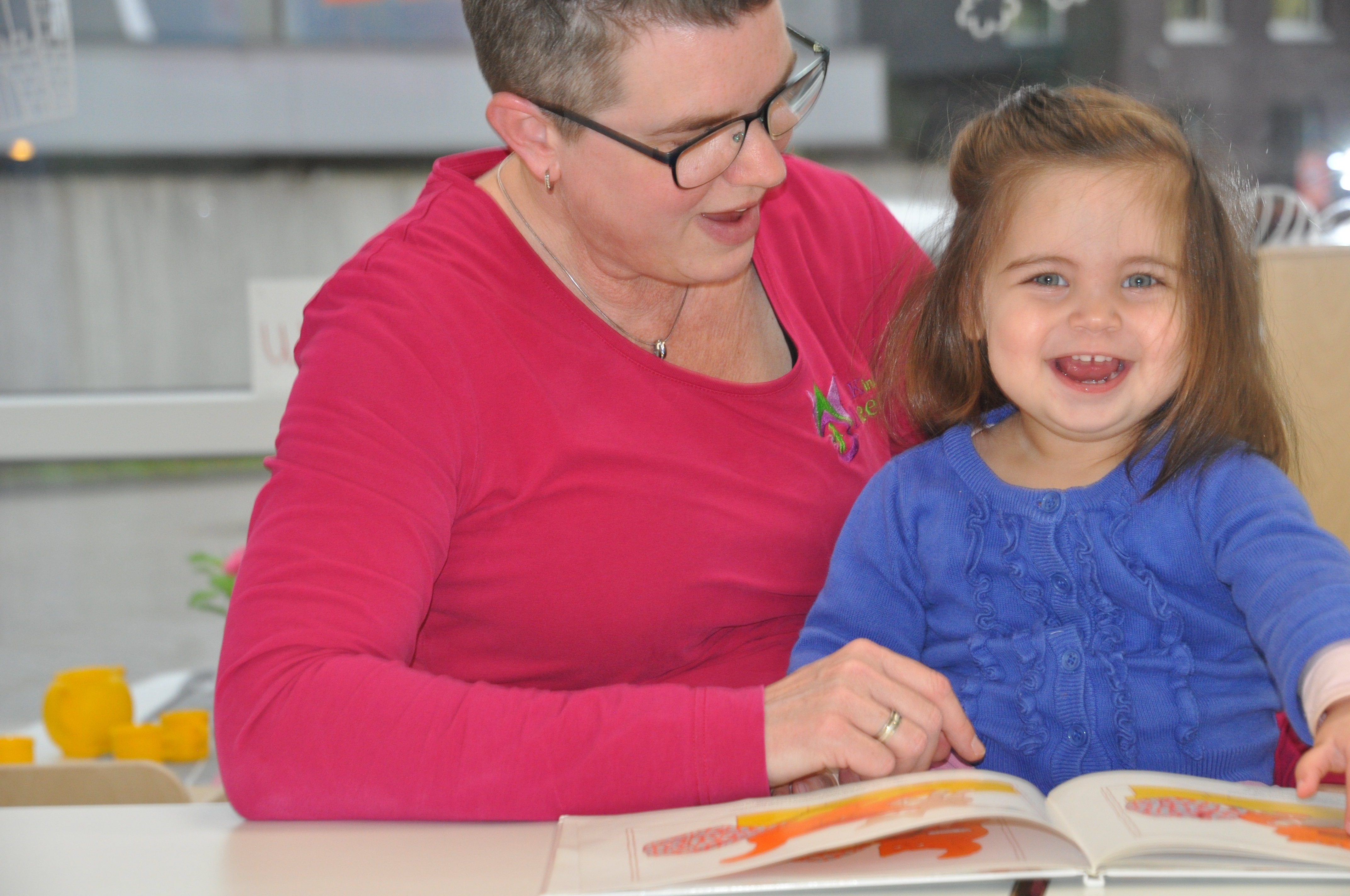 pedagogisch medewerker van kinderopvang meerdijk in Emmen leest samen met een meisje een kinderboek